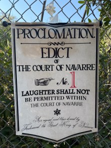 Humorous banner printed for Love' Labor's Lost play saying "Proclamation: Edict of The Court of Navarre No 1 - Laughter Shall Not be Permitted Within The Court of Navarre"